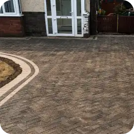 A large brick paver driveway and entryway showing weathered, faded colors from sun and elements requiring sealing protection.